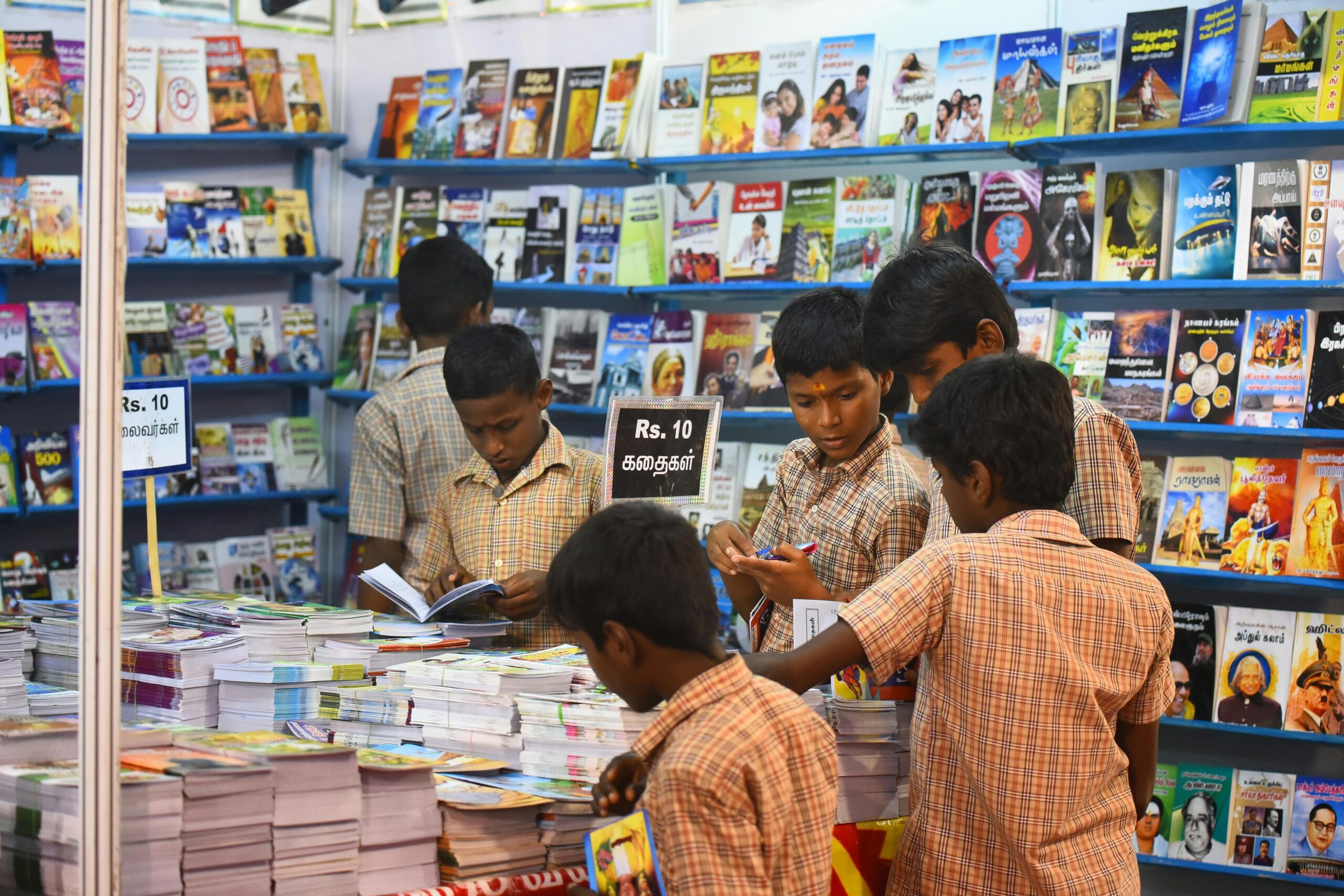 Children engaged in browsing books at a stall in Madurai, highlighting interest in reading and education.